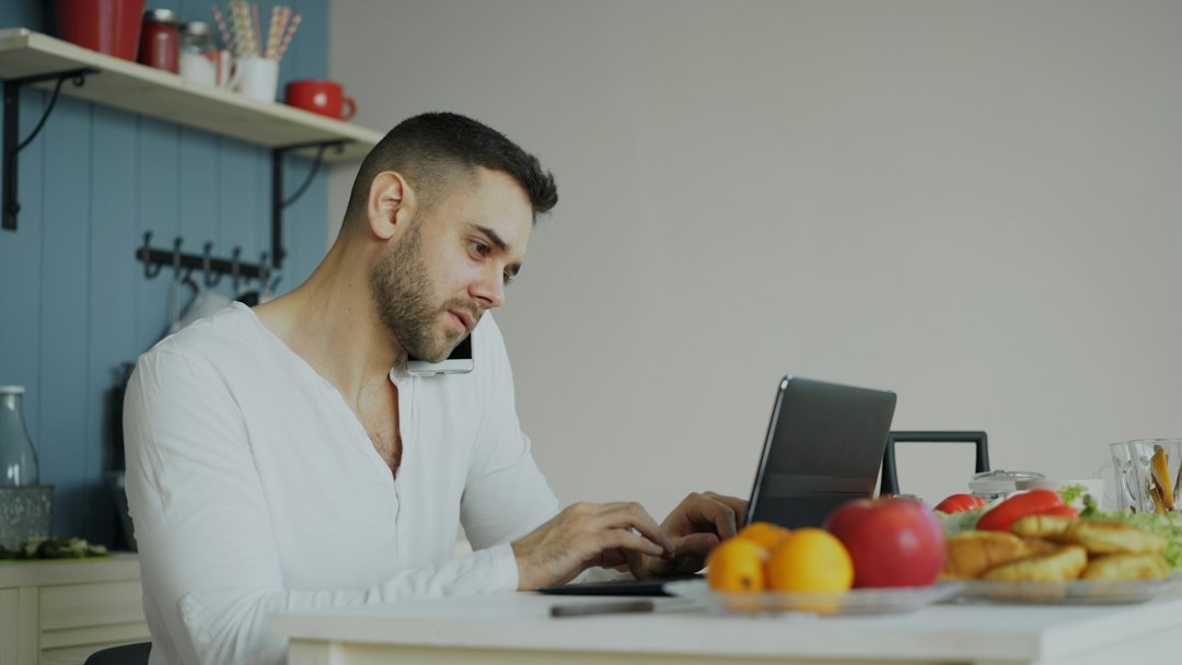 person typing on laptop at kitchen table